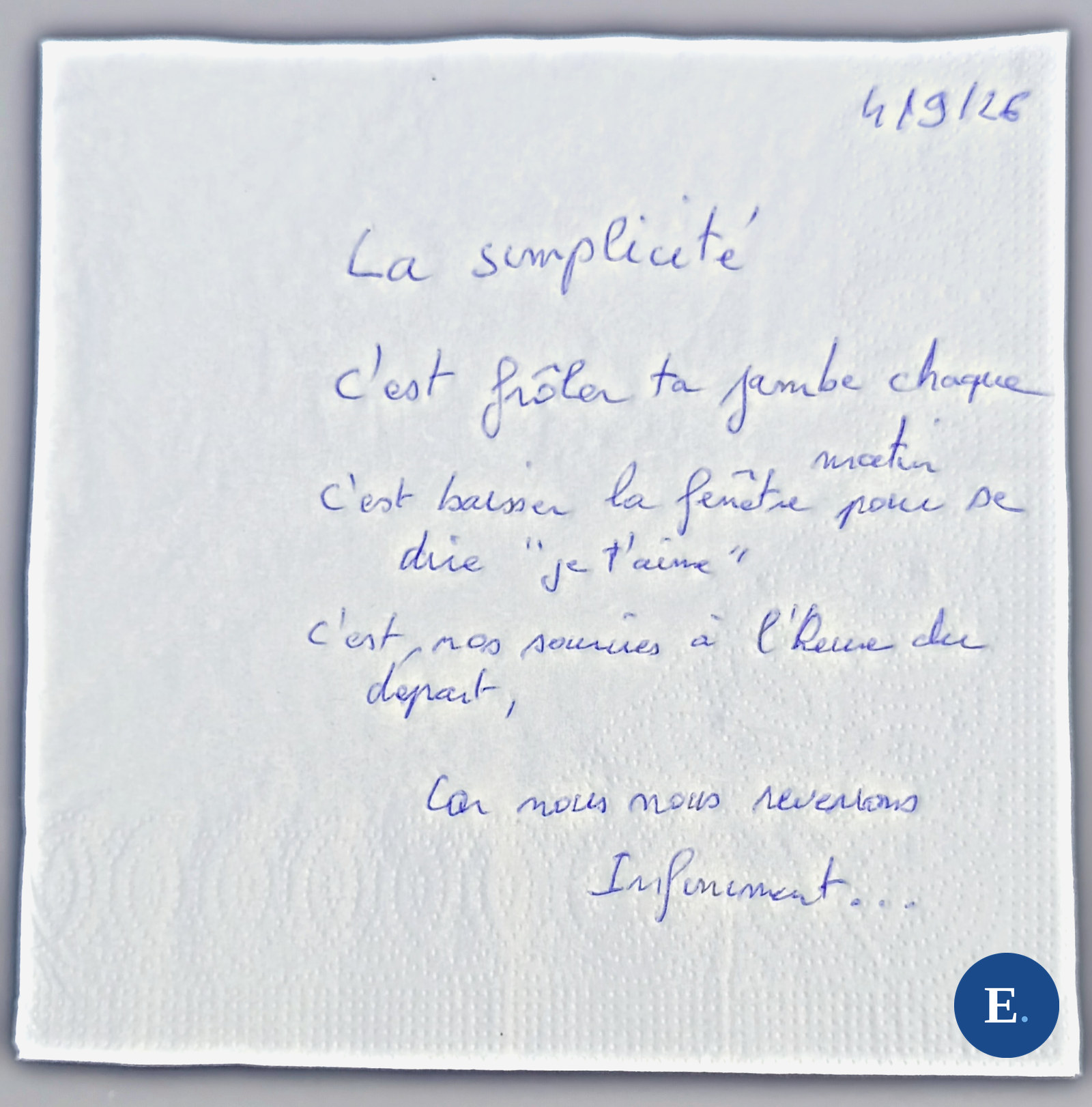 Serviette en papier blanche, gaufree, posee a plat sur un fond gris ; six lignes manuscrites a l encre bleue ; la date 4/9/26 dans le coin ; medaillon E. bleu en bas a droite.